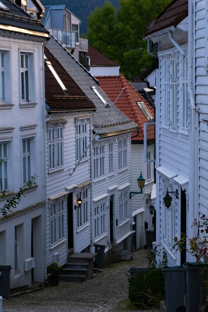 Hvit trebebyggelse langs smal gate — typisk norsk boligmasse der vinduer og etterisolering ofte vurderes